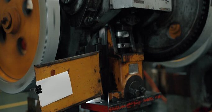 Close up of spinning flywheel and belt of industrial metal stamping press machine in factory