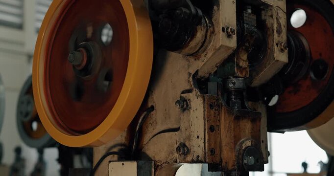 Close up of spinning flywheel and belt of industrial metal stamping press machine in factory