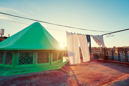 A rooftop view at sunset with a green conical structure and cityscape in the background. Fes Medina Morocco.