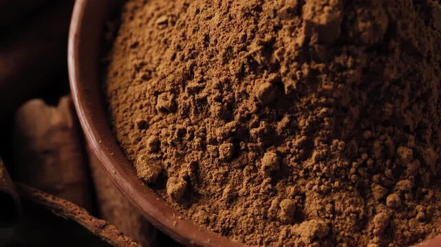 Ground cinnamon powder in a ceramic bowl, close-up view showing the fine texture and warm brown color, natural spice ingredient.	