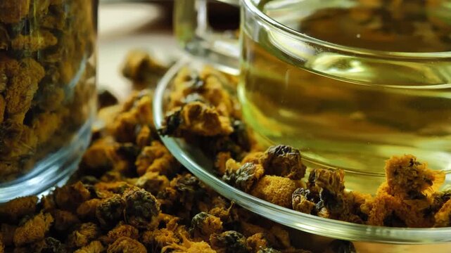 Dried chrysanthemum flowers displayed with a glass of chrysanthemum tea, highlighting a traditional floral herbal beverage