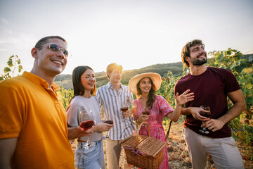 Obraz premium Group of friends looking away and enjoying sunset view in vineyard