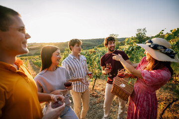 Obraz premium Young friends conversing and laughing together at vineyard wine tasting