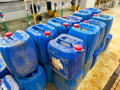 Stacked blue plastic jerry cans with red caps for liquid storage and transport