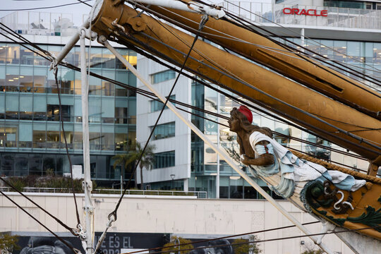 Low-angle perspective shows an ornate ship figurehead and rigging. 
