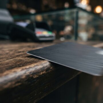 Credit card on wooden counter with payment terminal in background