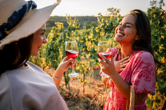 Two female friends sharing a heartfelt laugh while holding wine glasses