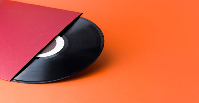 Vinyl Record and Red Sleeve on Orange Background with Copy Space