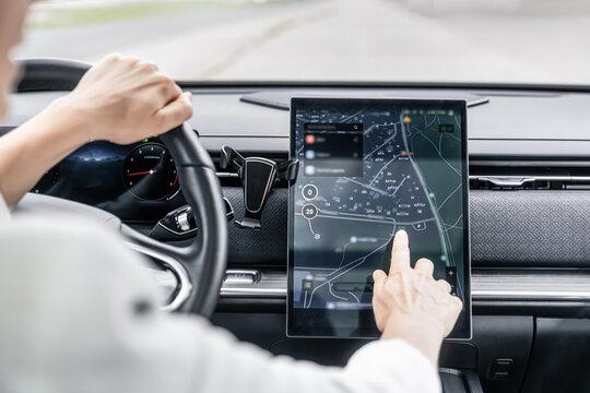 Woman driver using  gps navigation in city dark digital map interface on touchscreen display in modern car
