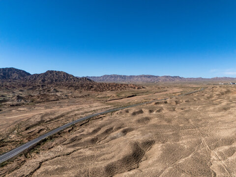 winding road traversing arid desert mountains under blue sky