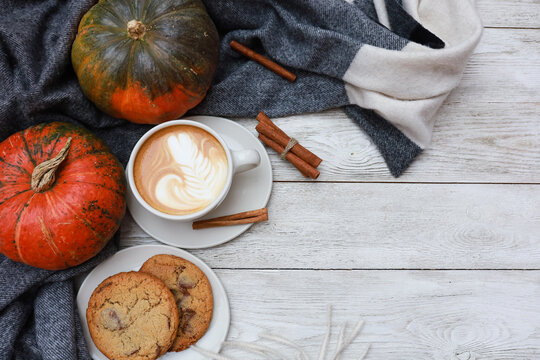 Cozy autumn coffee break, cup of latte with cookies, pumpkin at warm plaid on wooden table. Top view with copy pace. Thanksgiving menu template, harvest time, November morning 