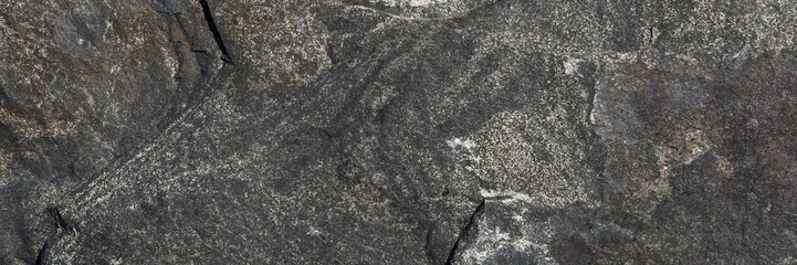 Dark natural stone texture with rough surface showing geological patterns and cracks © Harry