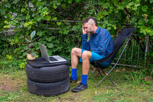 Frustrated remote worker using laptop at improvised backyard desk