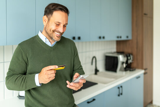 Man smiling while confidently holding a credit card and mobile phone, engaging in convenient online shopping and secure digital financial transactions