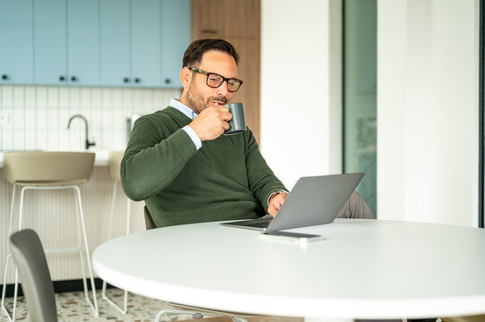Entrepreneur working on laptop at a modern workspace, enjoying a coffee break, managing business operations, accounting, and legal tasks remotely