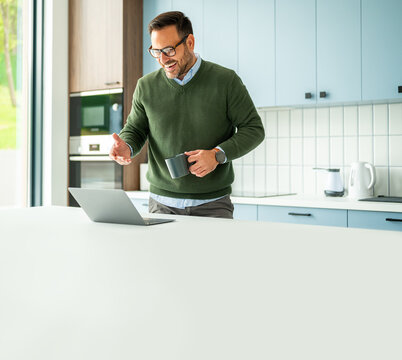 Male professional conducting a video conference call from his modern kitchen workspace, discussing financial strategies and legal bookkeeping through remote communication technology