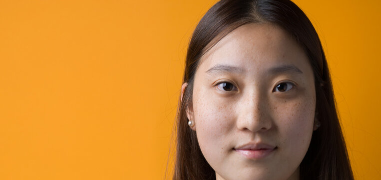 Natural Portrait of Young Chinese Woman Without Makeup on Yellow Background