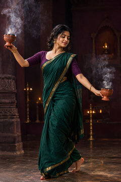 Graceful ritual woman dancing with smoking incense burners during durga puja navratri and diwali worship inside atmospheric traditional temple with glowing lamps