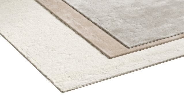 Stack of rectangular viscose rugs in different sizes and neutral shades, layered one over another with soft textures and subtle tonal variations, shown as a 3D render and visualization.