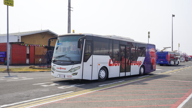 White Lion Group passenger shuttle bus driving on tarmac apron area at Hang Nadim International Airport, facilitating passenger flight transfers in Batam.