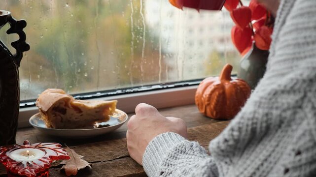 Autumn vibes. Woman drinking tea near window. Warm cozy fall mood. 