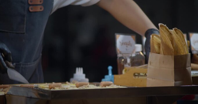 Street food vendor rolling a crepe on a hot griddle at a night market. Close-up of hands preparing dessert with batter and filling in an outdoor food stall setting.