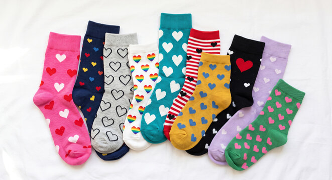 Colorful socks with heart patterns arranged on a white background