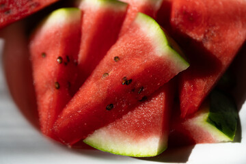 Close-up of juicy ripe watermelon slices with vivid red flesh and green rind. Fresh summer fruit background with rich natural texture © hannamartysheva