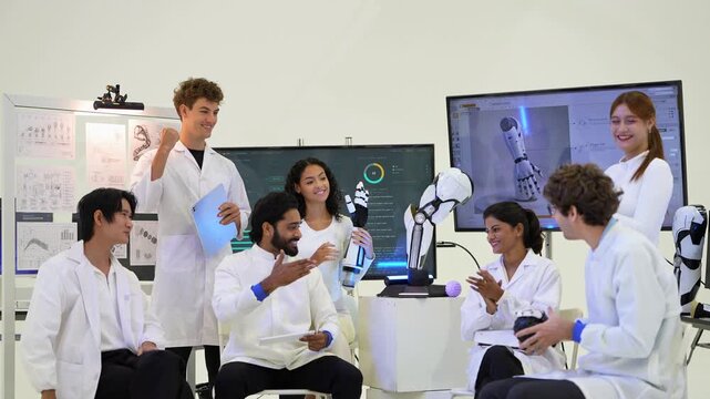 Cheerful robotics team in white coats laughs and applauds during a seated meeting beside a humanoid robot arm at an AI robotics lab, in a natural unposed moment, a smart automation concept