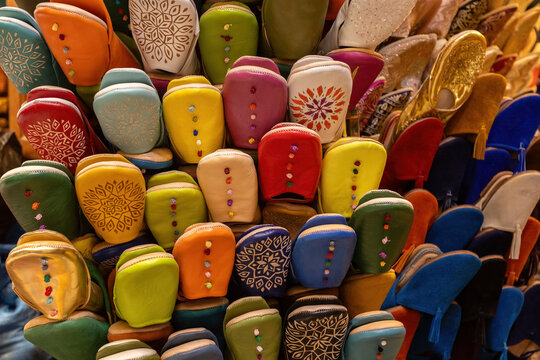 A vibrant display of traditional Moroccan babouche slippers, handcrafted with intricate embroidery and colorful leather, on sale in the medina of Fez, Morocco