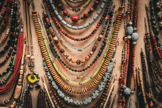A vibrant collection of traditional Moroccan beaded necklaces and jewelry displayed on fabric in a market stall in the medina of Fez, Morocco