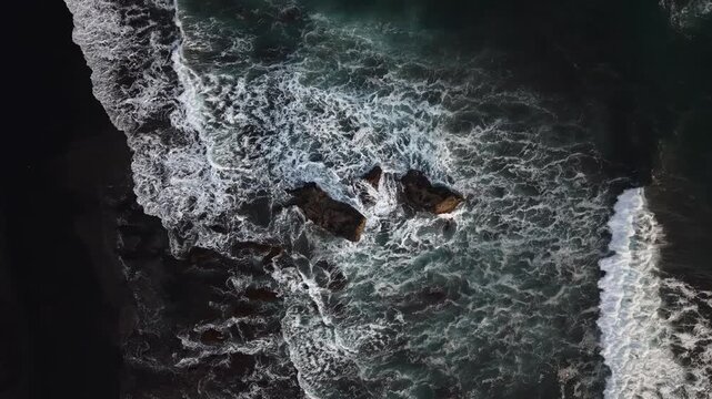 A vibrant aerial view of Kelecung Beach, Bali, shows turquoise waves crashing against jagged rock formations and tidal pools along the rugged coastline, evoking a sense of travel and natural beauty