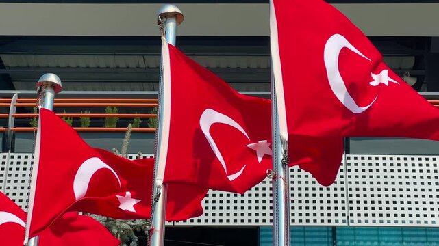Close up of multiple Turkish national flags waving in the wind in a public park in Istanbul, red banners on metal poles, repetition of national symbols, patriotism and urban public space concept