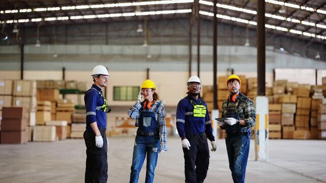 Team of four workers stands chatting in an empty storage hall, then turns around together and smiles toward the camera, real time 4K footage of timber industry work