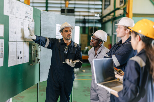 Professional senior lead supervisor engineer man training young engineers team in industry factory