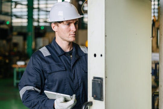 Professional Young Caucasian engineer male worker working control CNC machine in industry factory