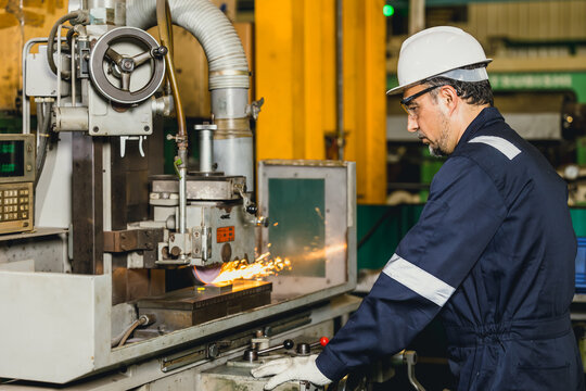 Industrial worker operating Surface Grinding Machine metalworking machine in heavy industry factory