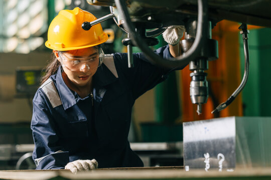 Professional Young Female industrial engineer worker quality operating industrial drilling machine.