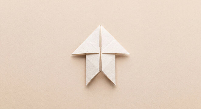 Origami paper arrow pointing up photo on beige background for growth and progress concept