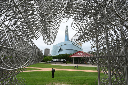 Winnipeg, Manitoba, Canada - July 2, 2026: A man in the park with a Canadian Museum for Human Rights in the background, Winnipeg, Manitoba.