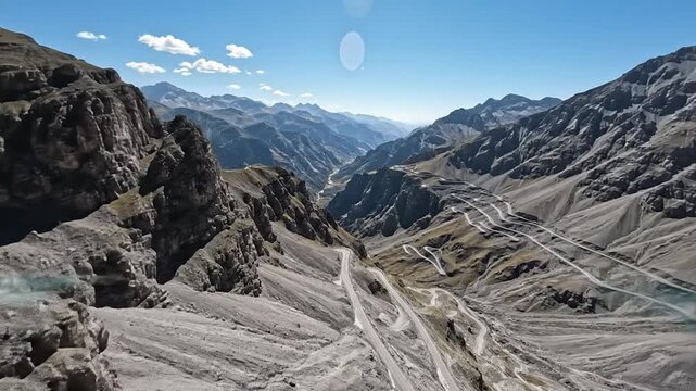 Aerial view of winding mountain pass road in the alps, dramatic altitude alpine landscape with serpentine curves and rugged peaks
