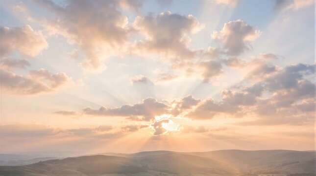 Golden sunbeams pierce soft clouds above rolling hills. Distant landmasses glow under warm, fading light. Sky bursts with peach, amber, and pale blue hues