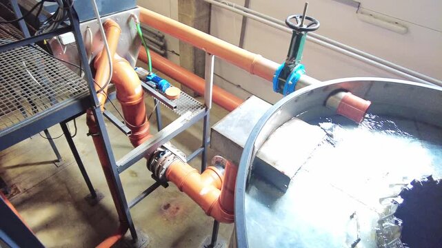 A large tank is filled with water used in a treatment process. Inside, rotating blades help mix and circulate the water. The tank also has a filtration system to ensure clean water. This setup shows 