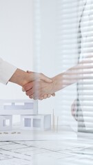 Professionals confirming a business deal, showing collaboration and mutual understanding in the architecture and construction industry, standing by plans and a safety helmet © rogerphoto