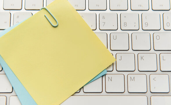 Yellow sticky note and paperclip on keyboard