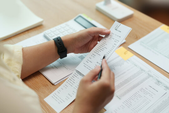 Woman reviewing a receipt and financial documents with a calculator at home. Budget planning and expense tracking help manage bills, debt and monthly finances.