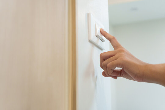 Close-up of a hand pressing a wall light switch to turn off electricity, symbolizing energy saving, home safety, efficient power use, and sustainable living.