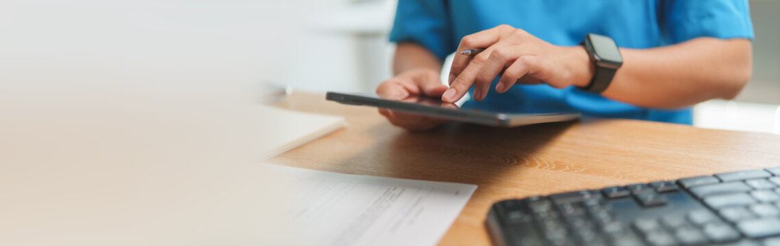 Medical professional using a digital tablet while working at a desk. Healthcare technology supports patient information, clinical review and medical data management.