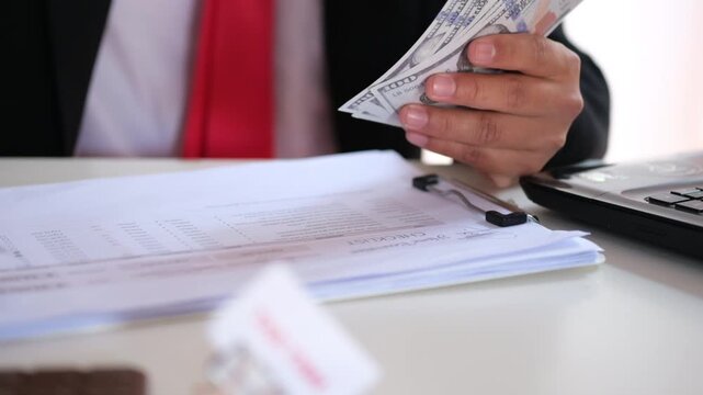 The accountant is counting cash and allocating it according to the previously prepared budget plan. Managing the company's financial expenditures.
