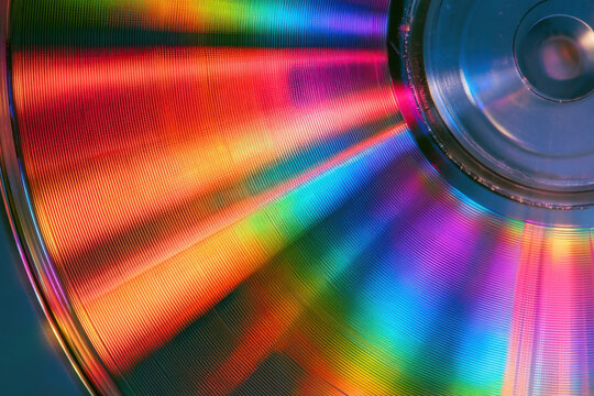 Close-up of compact disc surface showing colorful rainbow light diffraction patterns and reflections